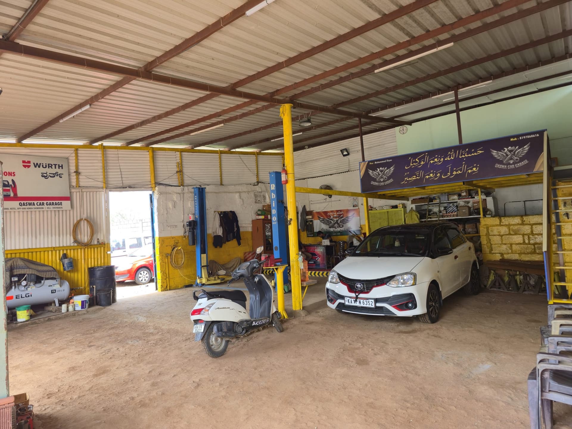 Workshop interior with lifts, compressor and cars under the metal roof